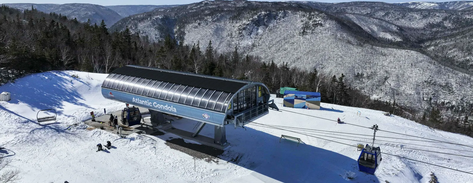 Atlantic Gondola summit station in winter, with a gondola cabin arriving over the snowy slope