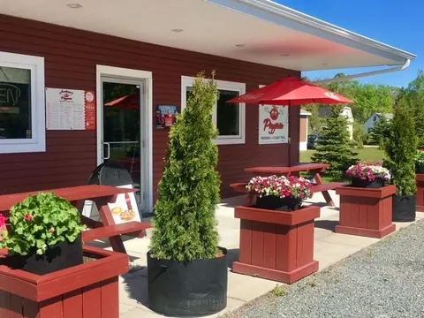 Red-painted Andrew’s Pizzeria with flower planters on the deck