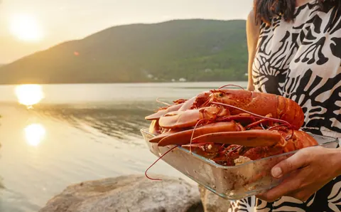 Plate of lobster held up by the water at sunset