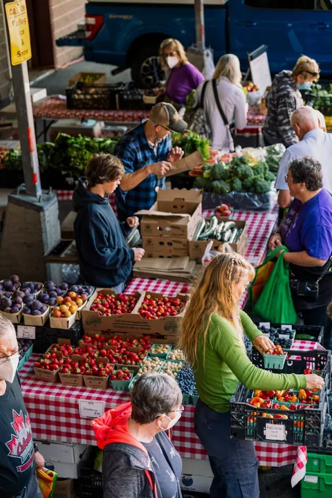 Shoppers at a busy farmer’s market stall of fresh produce
