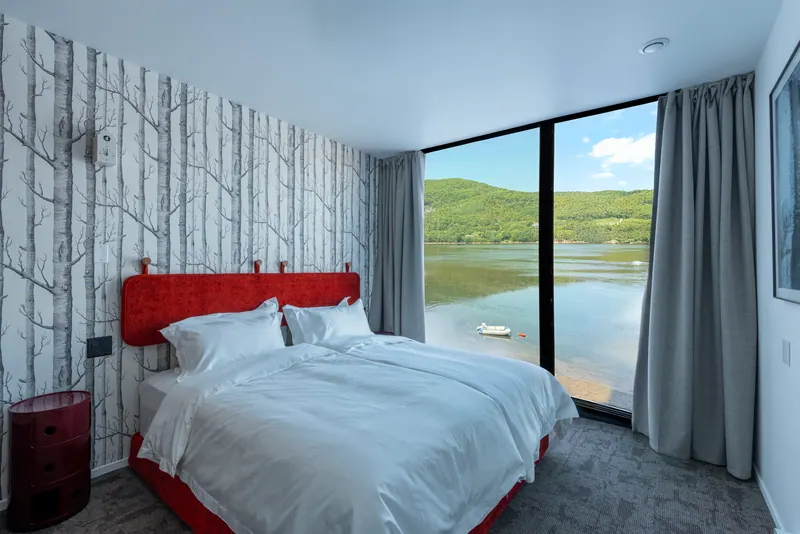 Bedroom at Cormorant Rock with a red headboard and a lake view