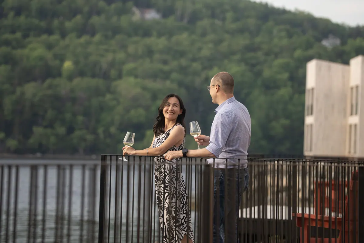 Couple with glasses of wine on a Cormorant Rock balcony above the water