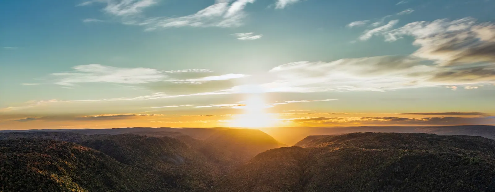 Sunset over the forested river valley of the Cape Breton Highlands