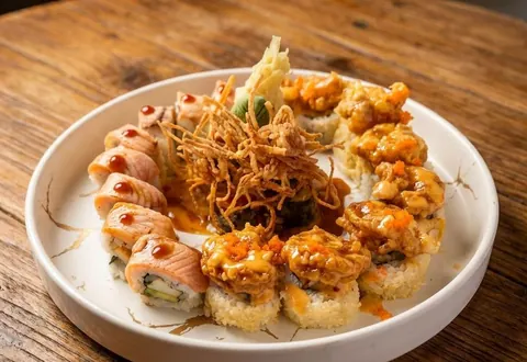 Plate of sushi rolls topped with crispy onions and spicy mayo