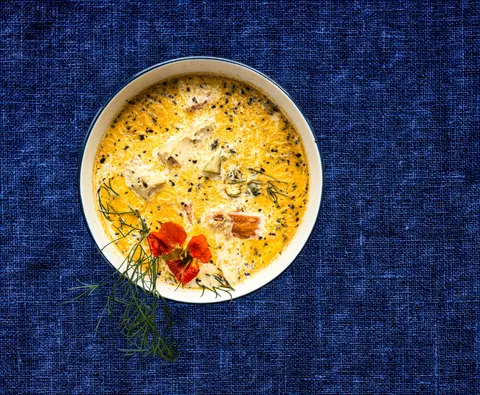 Bowl of creamy seafood chowder on a blue linen cloth
