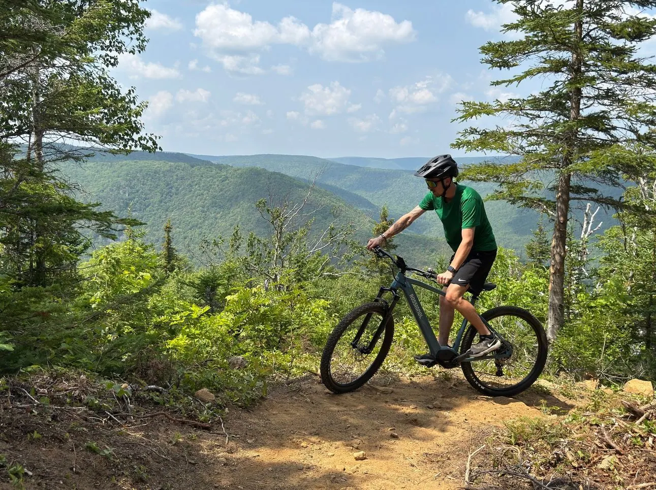 Mountain biker on a forest trail high above the green highlands valley