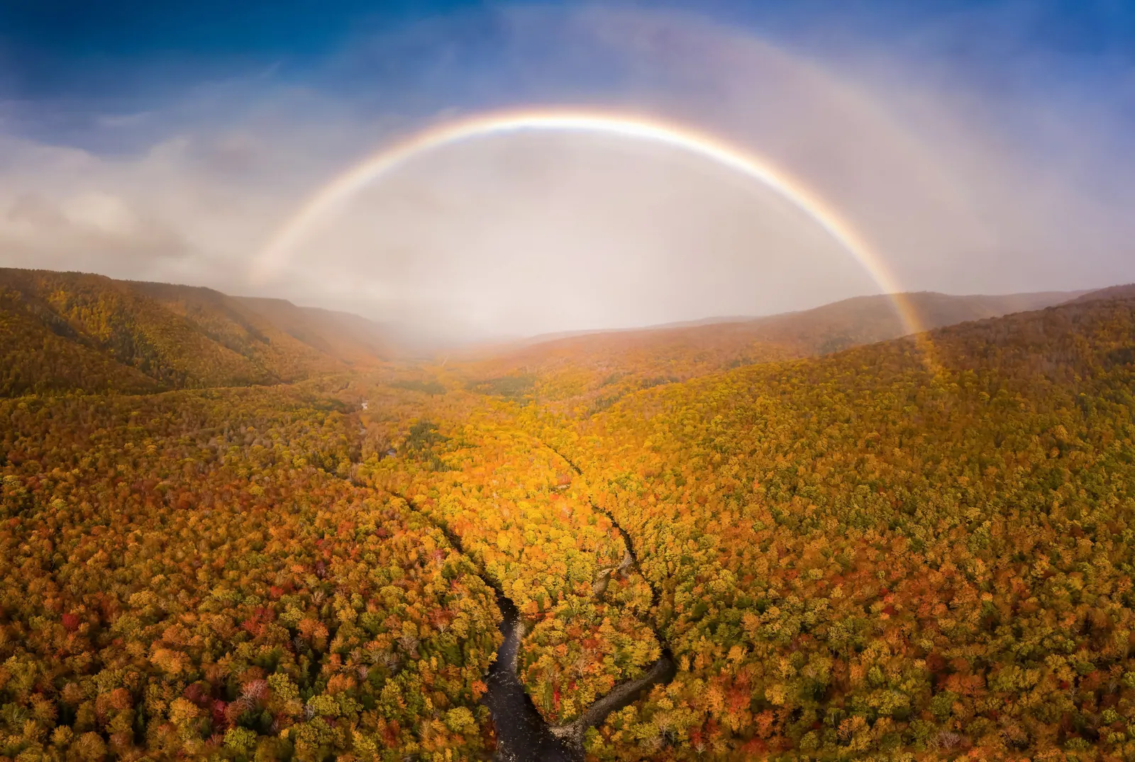 Autumn-coloured valley in the Cape Breton Highlands under a soft rainbow