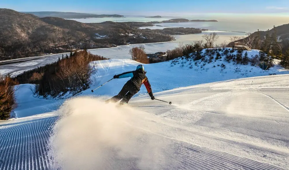 Skier carving a turn on a freshly groomed run, snow spraying from the skis