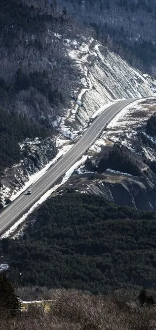 The Cabot Trail winding down a snowy mountainside above the coast