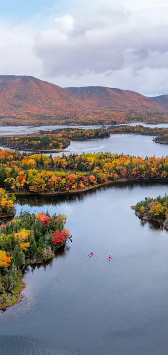Aerial view of islands covered in red and orange autumn trees on a calm lake