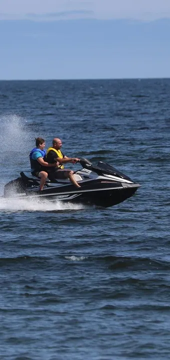 Two riders on a jet ski speeding across the ocean