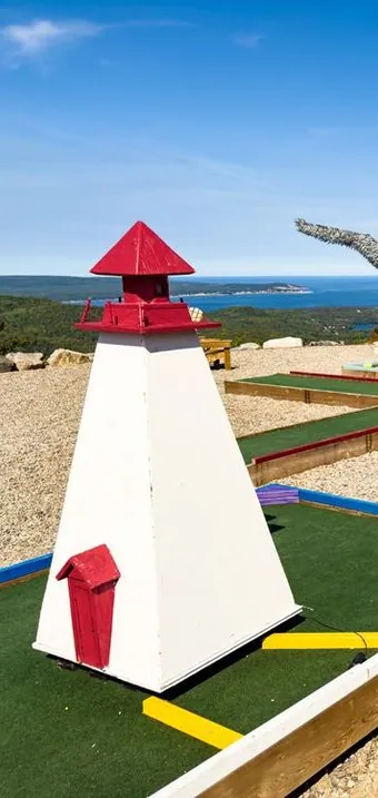 Mini golf course with a lighthouse model above the ocean
