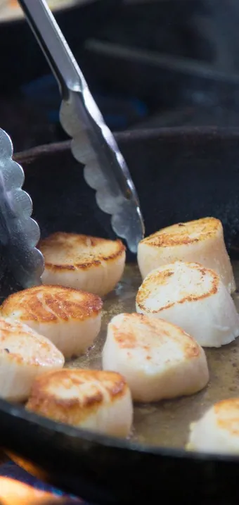 Scallops searing in a cast-iron pan