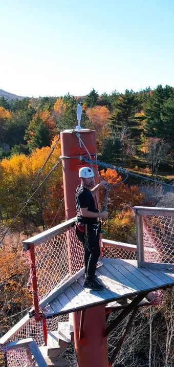 Person on a zip line platform above autumn forest