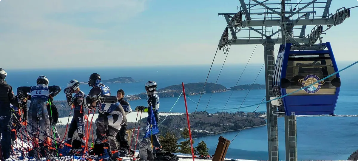 Ski racers at the summit beside the Atlantic Gondola, with the ocean and islands below