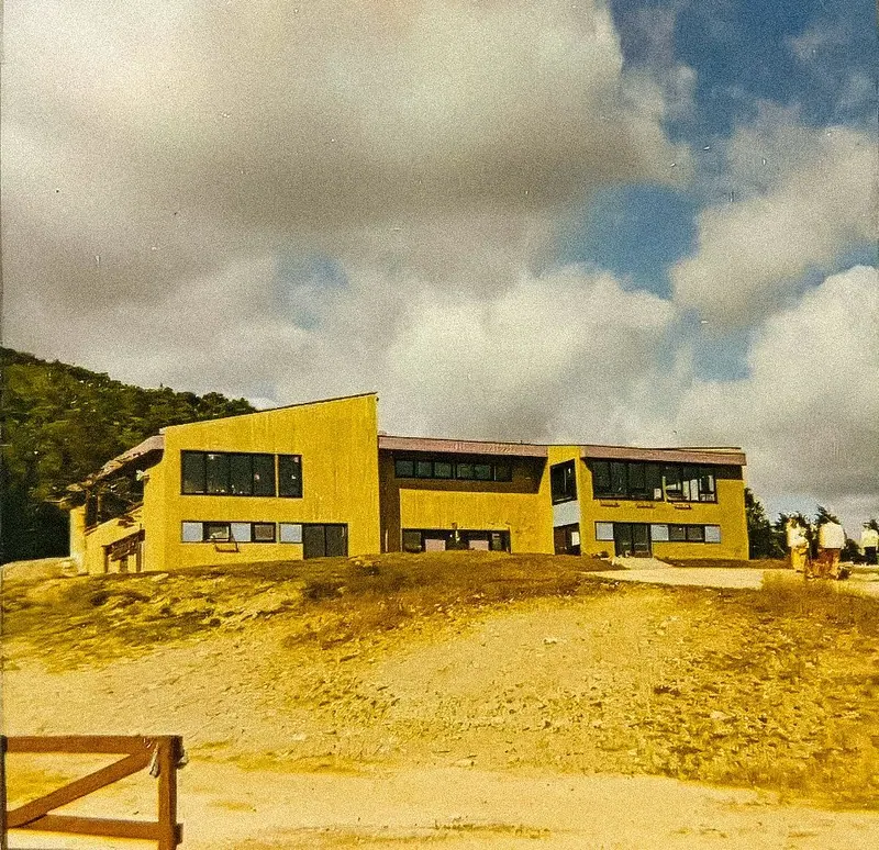 The original Cape Smokey ski lodge, a yellow two-storey building on the hilltop