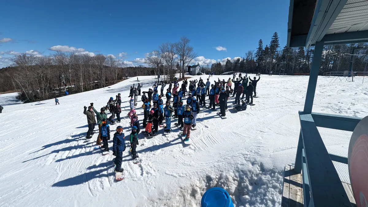 Large group of kids with skis gathered on the snowy slope during camp