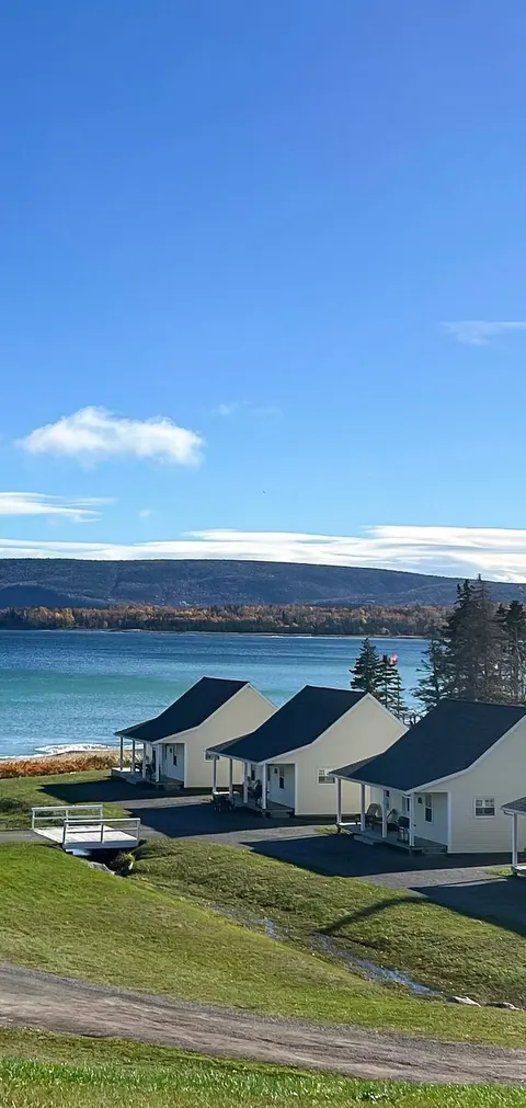 White cottages of Lantern Hill and Hollow on a green slope above the bay