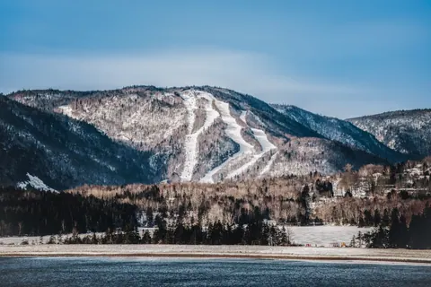 Snowy ski runs on the mountainside above the shore