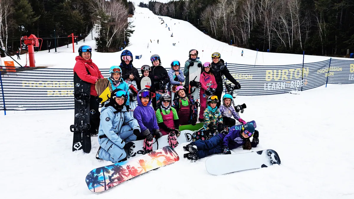 Group of young skiers and snowboarders posing together at the base of the hill