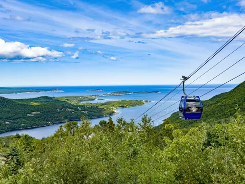 Atlantic Gondola cabin climbing above green forest with the bay and islands behind