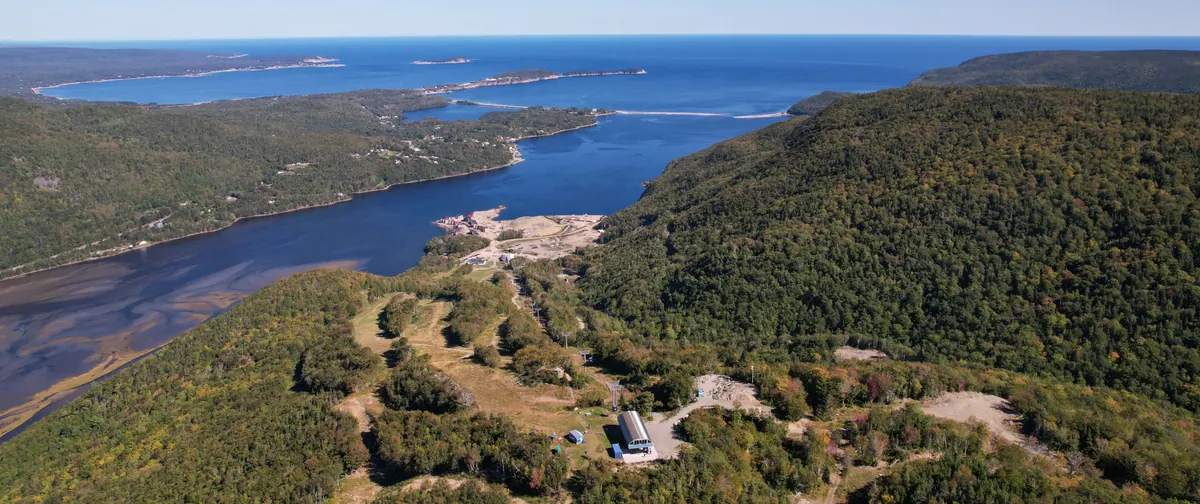 Aerial view of Cape Smokey’s green ski runs and summit base above a wide blue bay