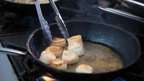 Scallops searing in a cast-iron pan