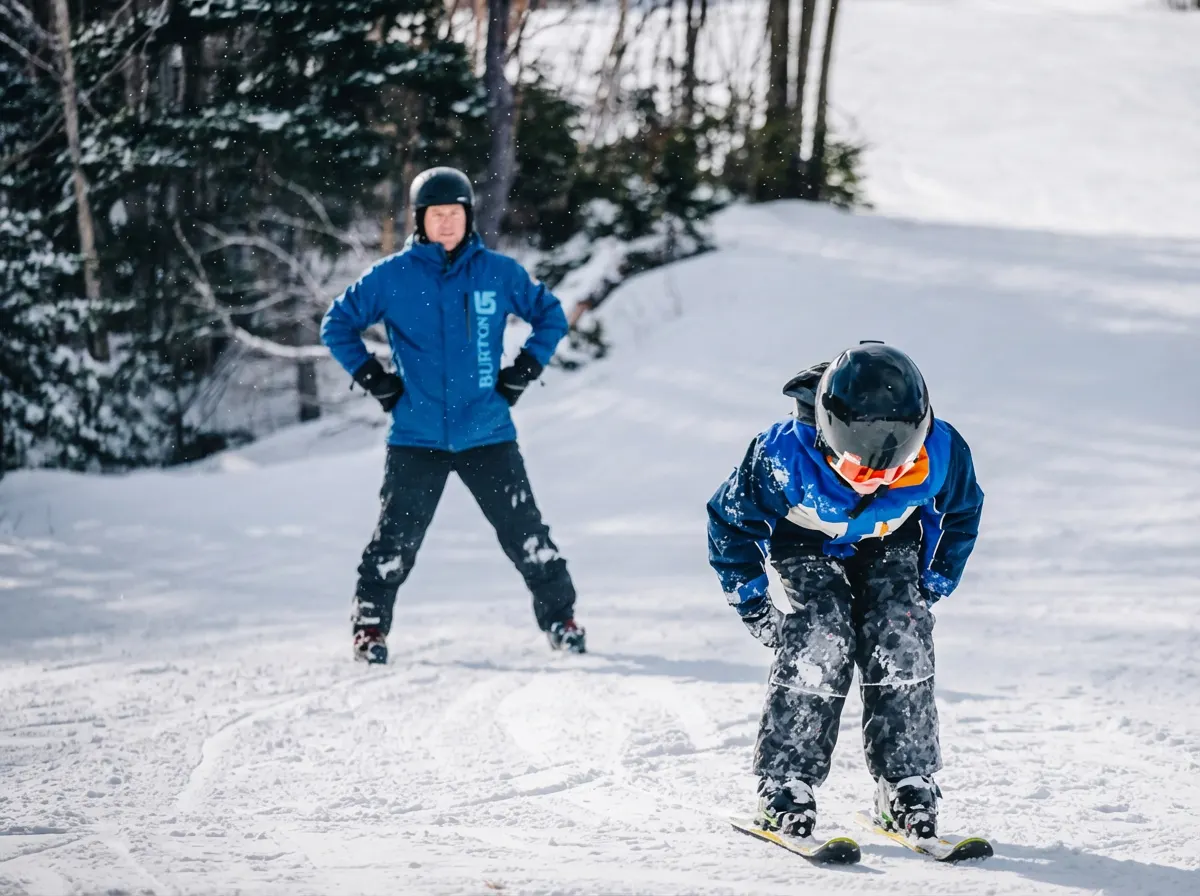 Ski instructor in a blue Cape Smokey jacket coaching a young skier on a snowy slope
