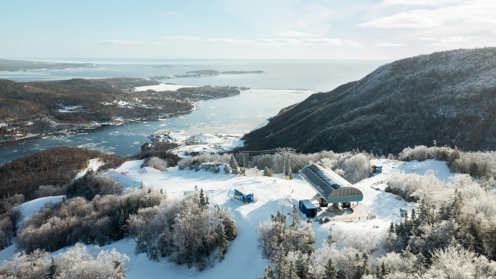 Aerial view of Cape Smokey with snow-covered slopes overlooking the ocean, showcasing rugged coastline and winter landscape.