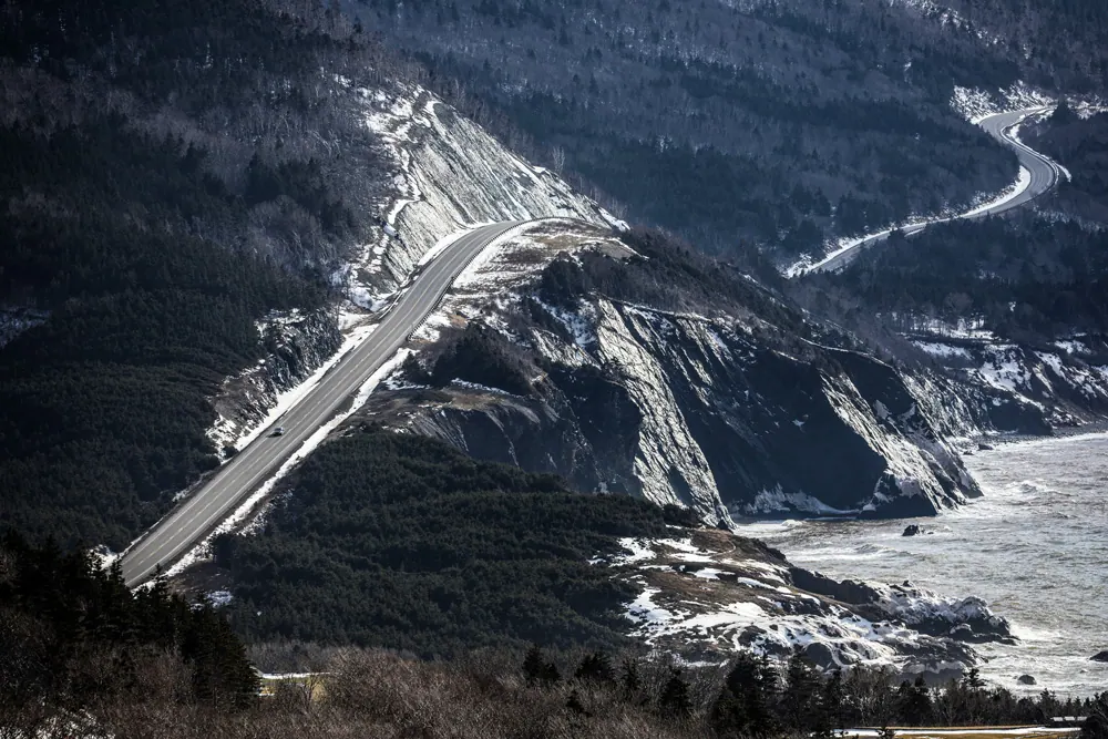 The Cabot Trail winding down a snowy mountainside above the coast