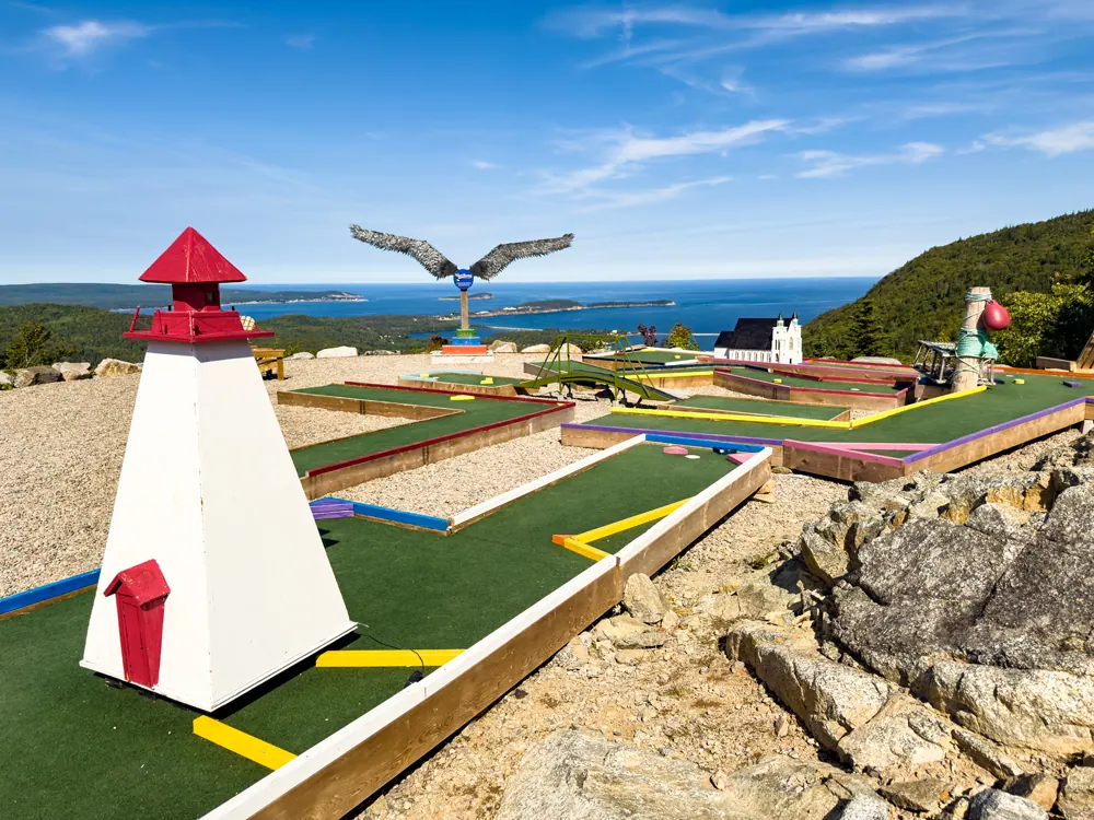 Mini golf course with a lighthouse model and an eagle sculpture above the ocean