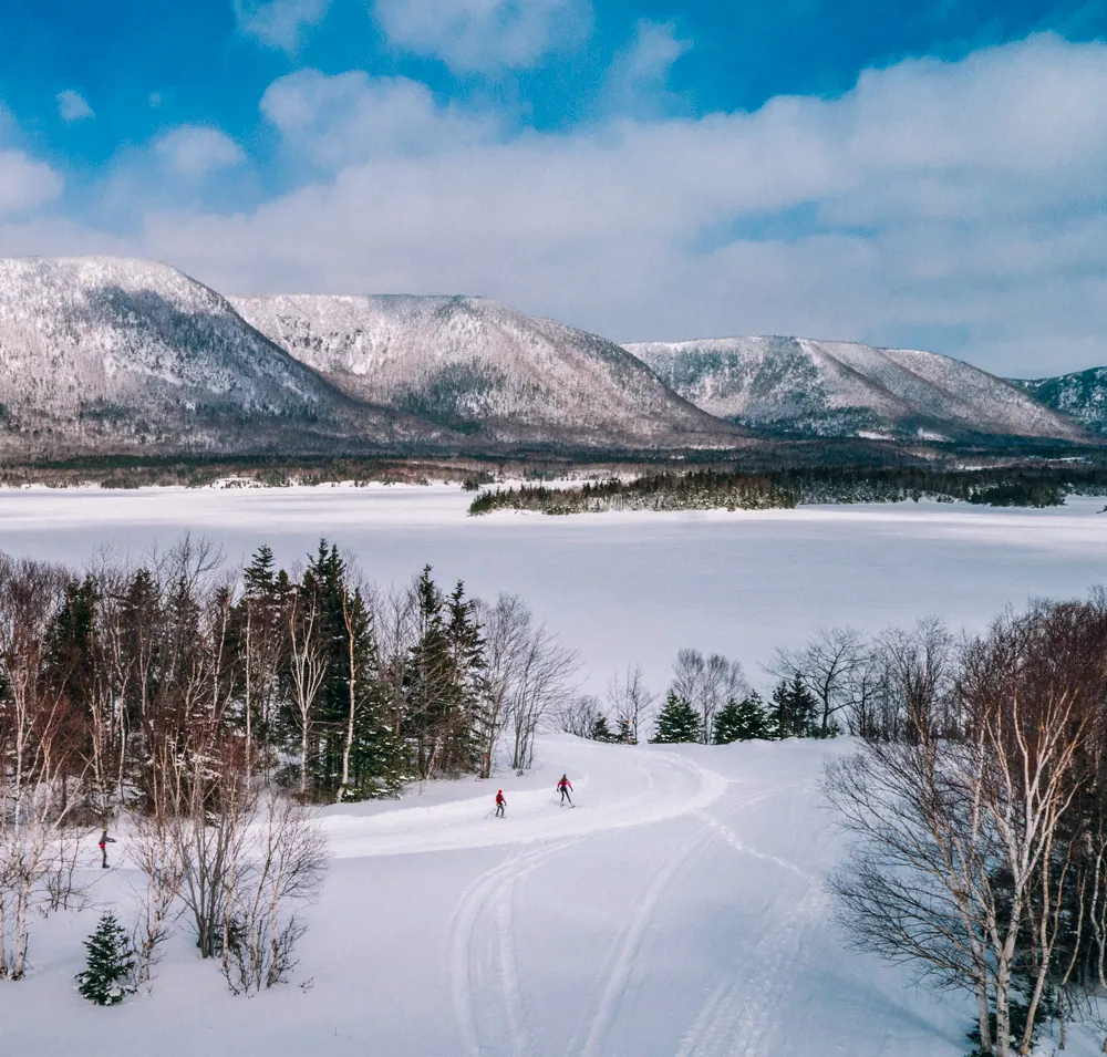 Cross-country skiers on a snowy trail below the highlands